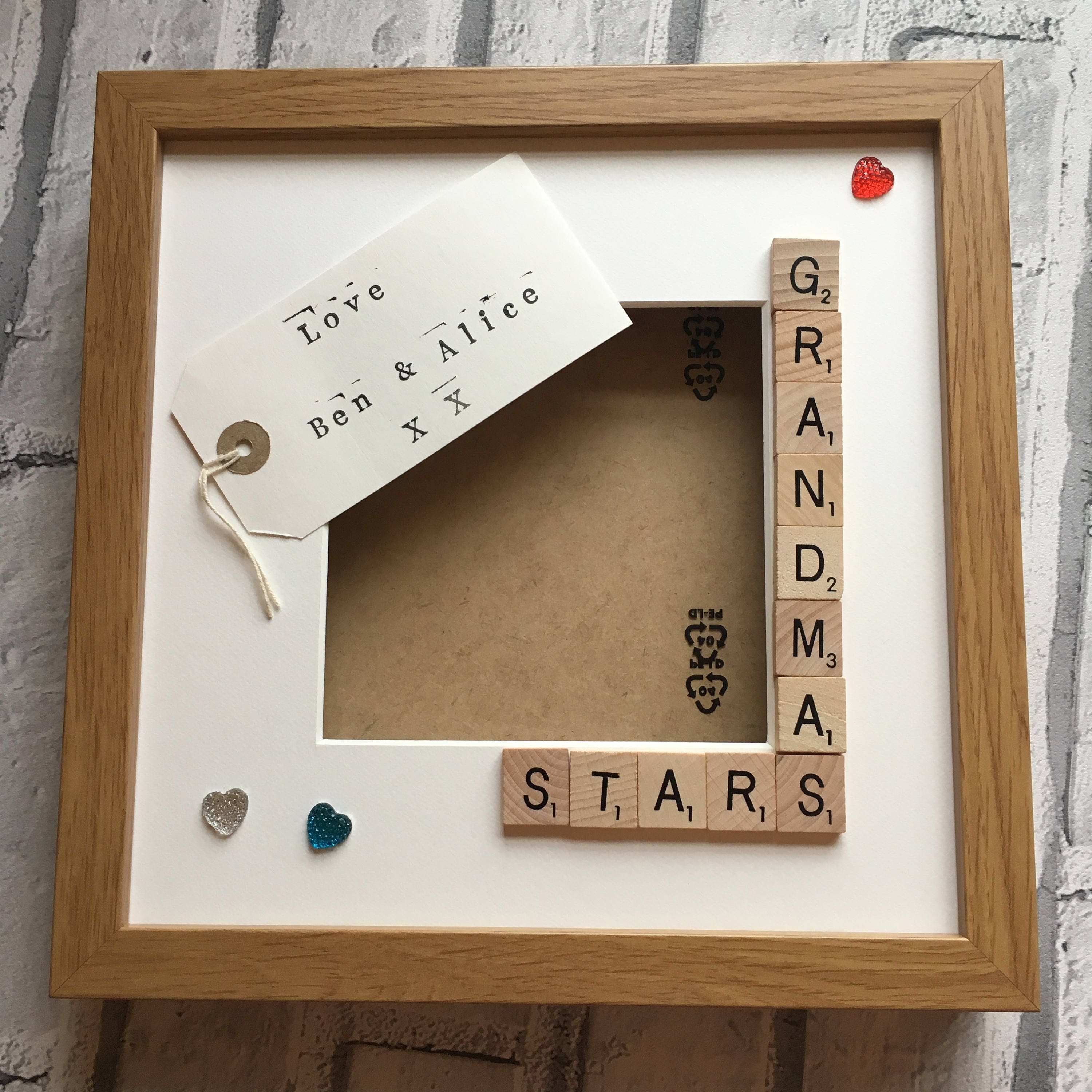 Wooden frame with scrabble tiles spelling 'GRANDMAS STARS' on a white background.