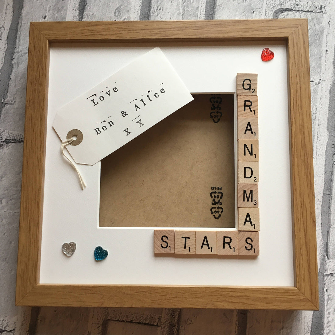 Wooden frame with scrabble tiles spelling 'GRANDMAS STARS' on a white background.